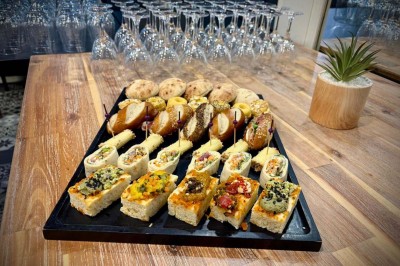 Bouteilles de vin, verres partiellement remplis et plateau de viennoiseries sur une table en bois dans un espace intérieur.