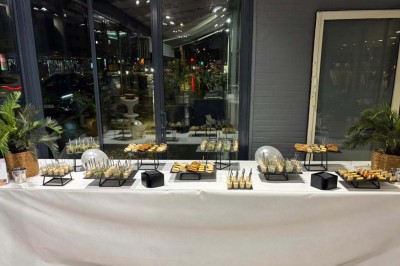 Bouteilles de vin, verres partiellement remplis et plateau de viennoiseries sur une table en bois dans un espace intérieur.