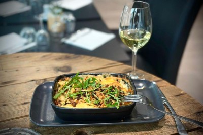 Bouteilles de vin, verres partiellement remplis et plateau de viennoiseries sur une table en bois dans un espace intérieur.