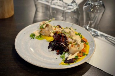 Bouteilles de vin, verres partiellement remplis et plateau de viennoiseries sur une table en bois dans un espace intérieur.