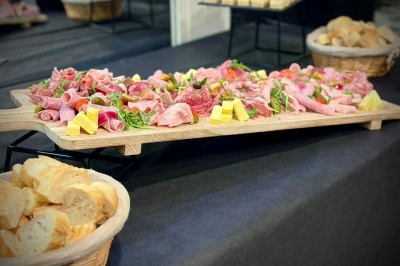 Bouteilles de vin, verres partiellement remplis et plateau de viennoiseries sur une table en bois dans un espace intérieur.