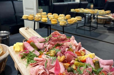 Bouteilles de vin, verres partiellement remplis et plateau de viennoiseries sur une table en bois dans un espace intérieur.