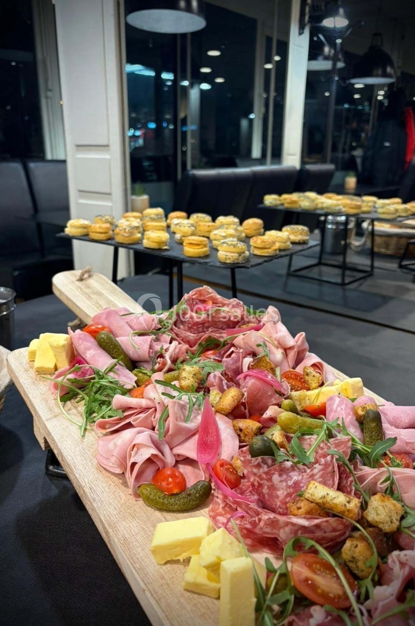 Plateau de charcuterie avec fromages, légumes marinés et pain grillé, en arrière-plan des petits choux disposés sur des…