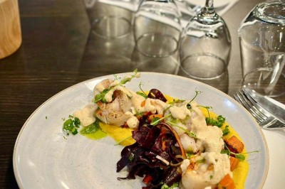 Bouteilles de vin, verres partiellement remplis et plateau de viennoiseries sur une table en bois dans un espace intérieur.