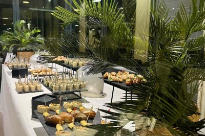Bouteilles de vin, verres partiellement remplis et plateau de viennoiseries sur une table en bois dans un espace intérieur.