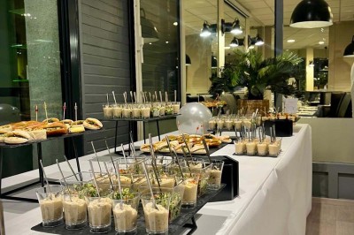 Bouteilles de vin, verres partiellement remplis et plateau de viennoiseries sur une table en bois dans un espace intérieur.