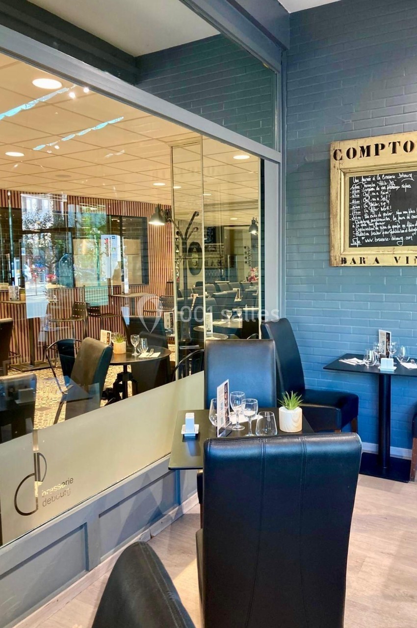 Salle de restaurant moderne avec tables dressées, vue sur un tableau de menu et une décoration sobre.