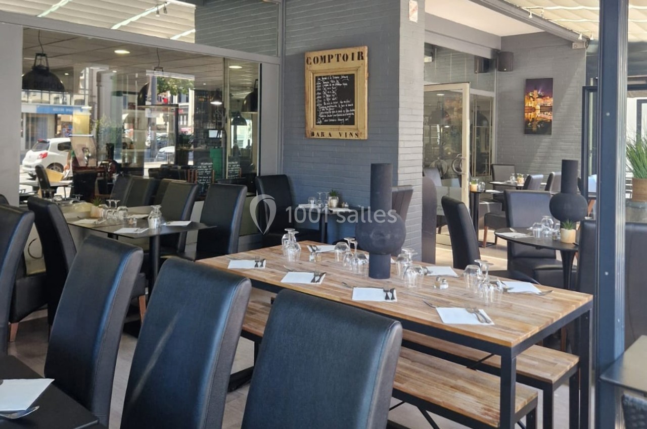 Salle de restaurant moderne avec tables en bois, chaises noires et décoration sobre, prête pour accueillir des clients.