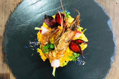 Assiette de dessert composée de meringues, éclats de caramel, feuilles de menthe et miettes de biscuit noir.