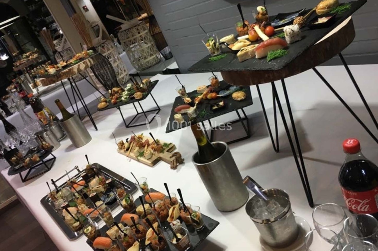 Buffet avec diverses bouchées salées et sucrées disposées sur des plateaux, accompagné de boissons et de verres.