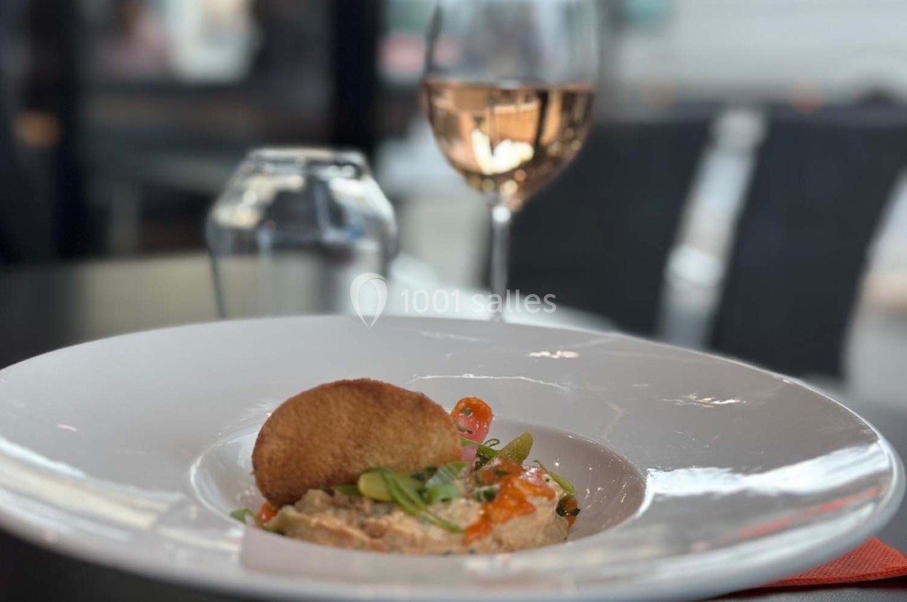 Assiette de plat raffiné avec garniture, accompagnée d'un verre de vin rosé sur une table de restaurant.