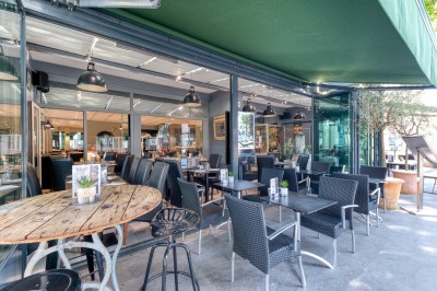 Miniature Location salle Lyon 7 (Rhône) - Brasserie Debourg #61 Comptoir de bar moderne avec revêtement en bois, étagères de bouteilles, tables hautes et décoration végétale.