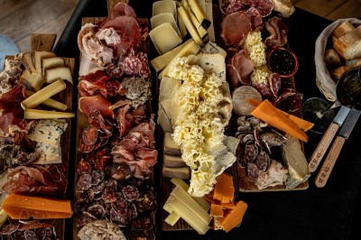 Fondue au fromage dans un caquelon rouge avec des morceaux de pain trempés, accompagnée de vin et de cornichons.