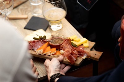 Miniature Traiteur Paris 9 (Paris) - Le 17.45 Paris #9 Fondue au fromage dans un caquelon rouge, avec du pain trempé sur des fourchettes, accompagnée de vin et de cornichons.
