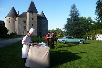 Vue d'un château en pierre entouré d'arbres et d'une pelouse bien entretenue sous un ciel dégagé.