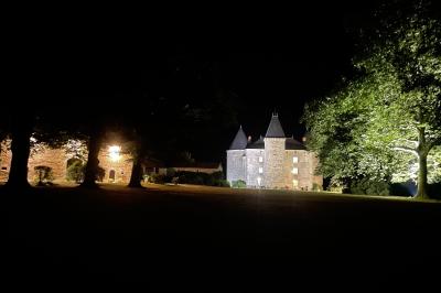 Vue d'un château en pierre entouré d'arbres et d'une pelouse bien entretenue sous un ciel dégagé.