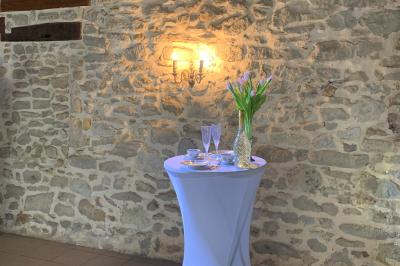 Salle de réception décorée avec des tables dressées, nappes blanches, bouquets de roses et chaises blanches.
