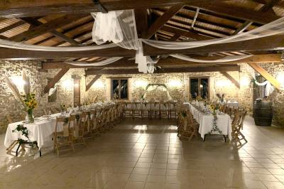 Salle de réception décorée avec des tables dressées, nappes blanches, bouquets de roses et chaises blanches.