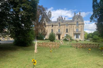 Salle de réception décorée avec des tables dressées, nappes blanches, bouquets de roses et chaises blanches.