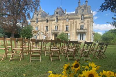 Salle de réception décorée avec des tables dressées, nappes blanches, bouquets de roses et chaises blanches.