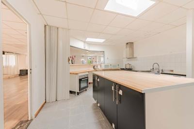 Chambre lumineuse avec lit double, tables de chevet, lampes, sol en bois clair et fenêtres donnant sur l'extérieur.