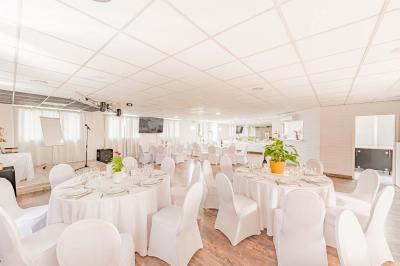 Chambre lumineuse avec lit double, tables de chevet, lampes, sol en bois clair et fenêtres donnant sur l'extérieur.