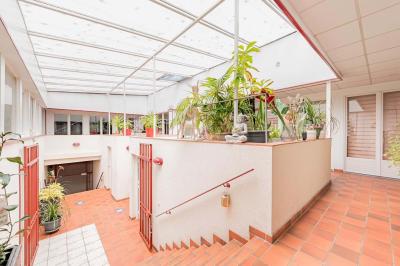 Chambre lumineuse avec lit double, tables de chevet, lampes, sol en bois clair et fenêtres donnant sur l'extérieur.