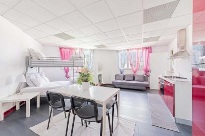 Chambre lumineuse avec lit double, tables de chevet, lampes, sol en bois clair et fenêtres donnant sur l'extérieur.