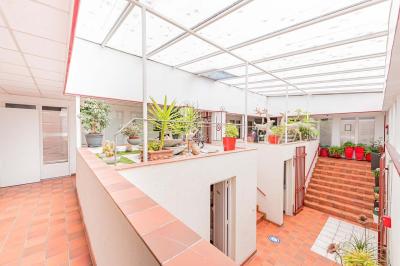 Chambre lumineuse avec lit double, tables de chevet, lampes, sol en bois clair et fenêtres donnant sur l'extérieur.