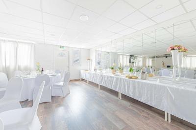 Chambre lumineuse avec lit double, tables de chevet, lampes, sol en bois clair et fenêtres donnant sur l'extérieur.