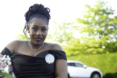 Panier cadeau contenant des friandises, des ballons dorés et des décorations, posé sur une voiture.