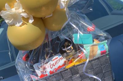 SUV noir décoré d'un bouquet de fleurs sur le capot, stationné sur un parking entouré de végétation.