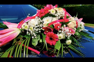 SUV noir décoré d'un bouquet de fleurs sur le capot, stationné sur un parking entouré de végétation.