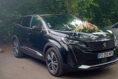SUV noir décoré d'un bouquet de fleurs sur le capot, stationné sur un parking entouré de végétation.