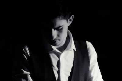 Voiture sportive bleue stationnée sur une place pavée devant un monument en bronze et des bâtiments historiques.