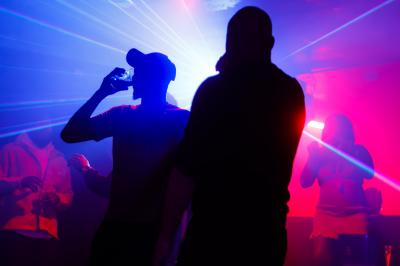 Voiture sportive bleue stationnée sur une place pavée devant un monument en bronze et des bâtiments historiques.