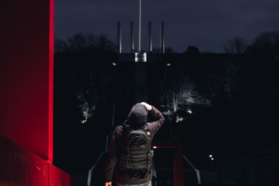 Voiture sportive bleue stationnée sur une place pavée devant un monument en bronze et des bâtiments historiques.