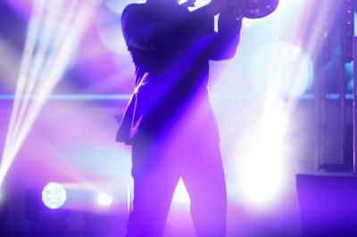 Voiture sportive bleue stationnée sur une place pavée devant un monument en bronze et des bâtiments historiques.