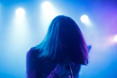 Voiture sportive bleue stationnée sur une place pavée devant un monument en bronze et des bâtiments historiques.