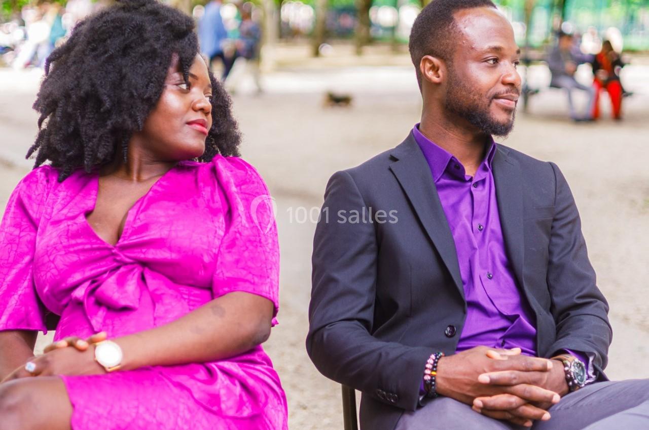Un homme et une femme assis sur des chaises dans un parc verdoyant, discutant dans une ambiance détendue.