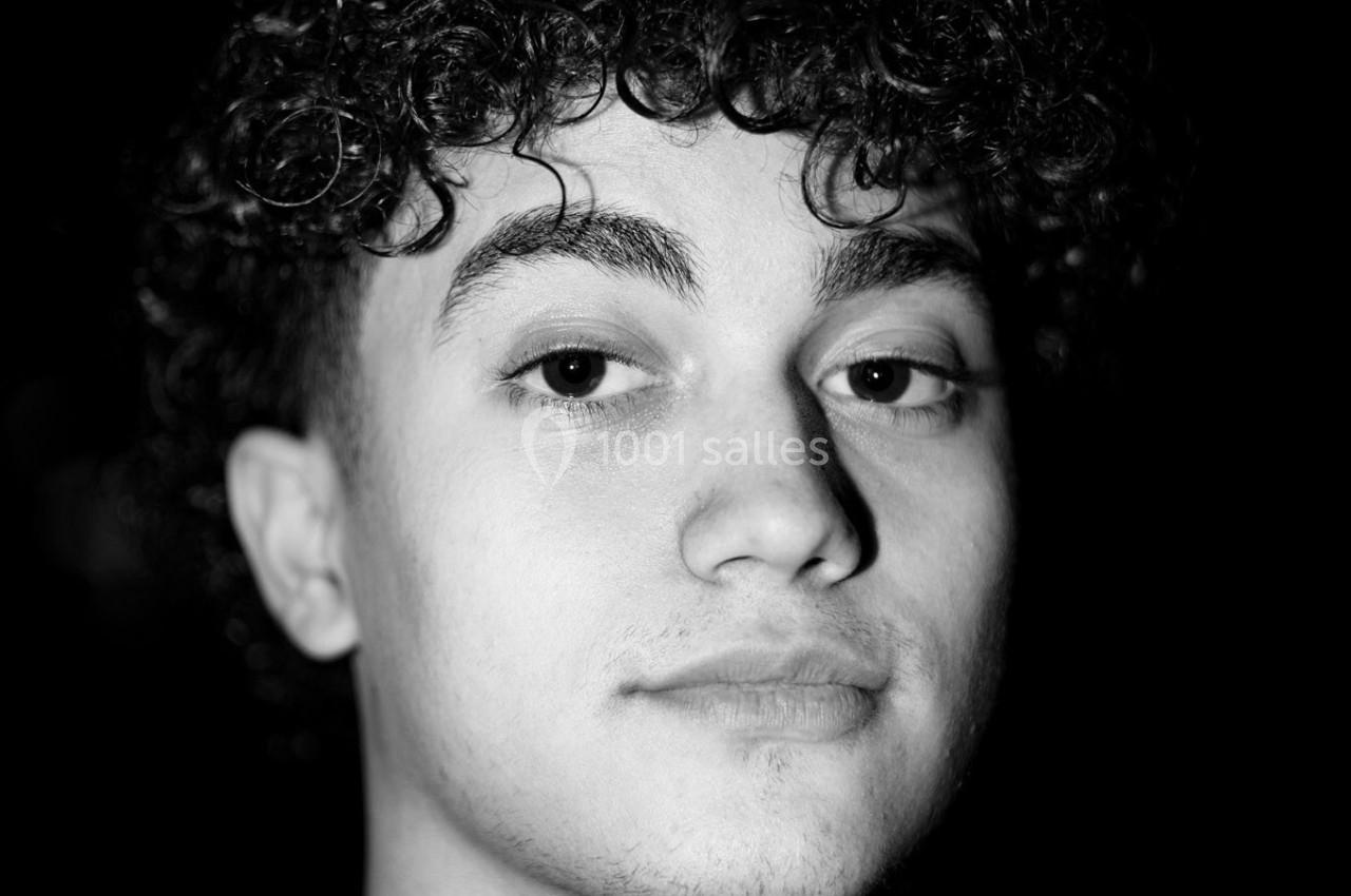 Portrait en noir et blanc d'un jeune homme aux cheveux bouclés, regardant directement vers l'objectif.