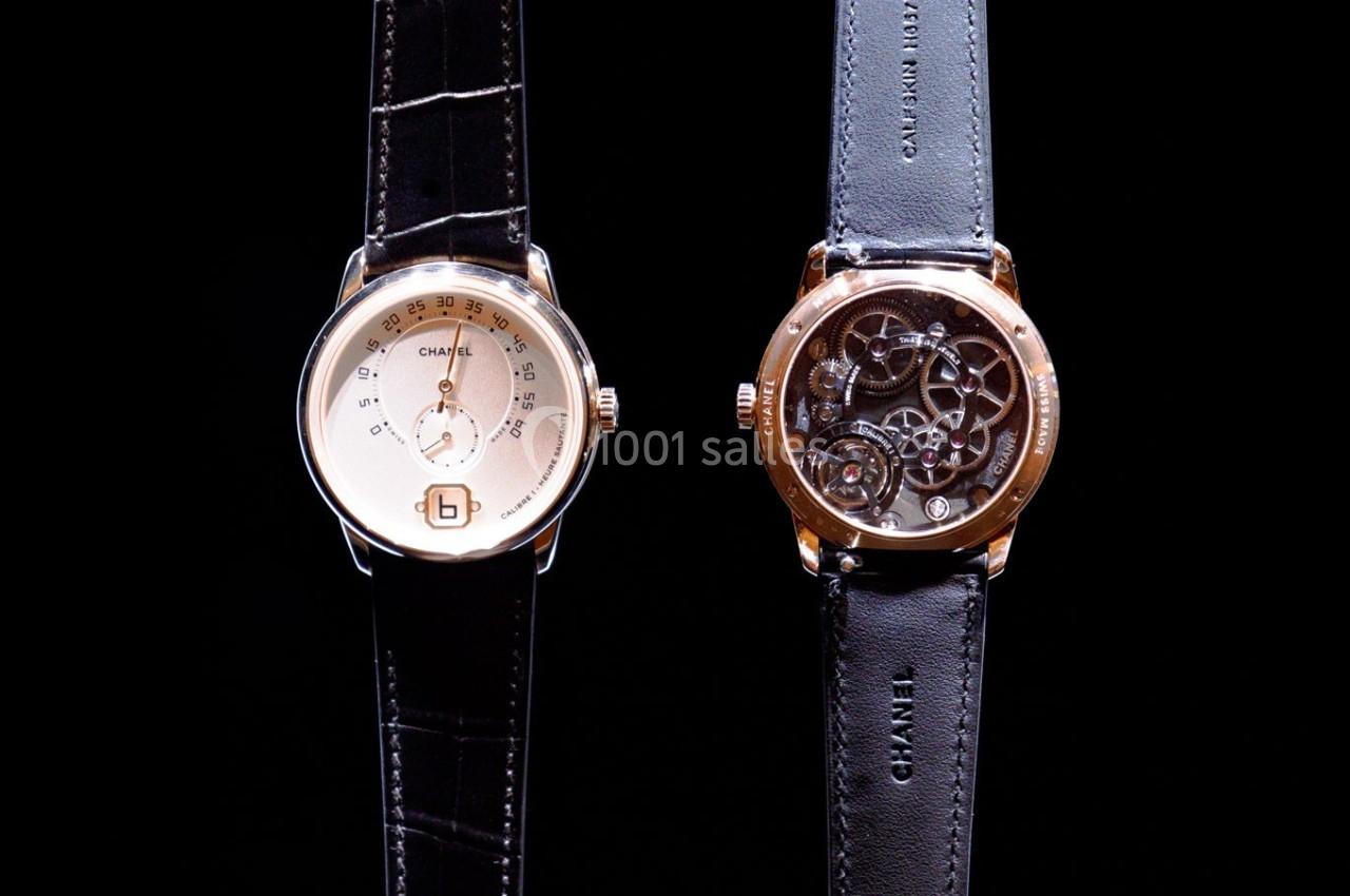 Deux montres-bracelets en cuir noir, une avec cadran doré et l'autre montrant un mécanisme visible au dos.