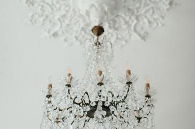 Un couple de mariés marche vers un château en pierre avec des volets blancs, entouré de quelques invités.