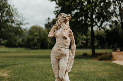 Un couple de mariés marche vers un château en pierre avec des volets blancs, entouré de quelques invités.
