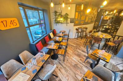 Des mains trinquent avec des verres au-dessus d'une table garnie de charcuterie, fromages et pains.