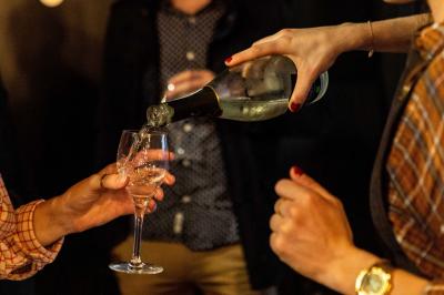 Des mains trinquent avec des verres au-dessus d'une table garnie de charcuterie, fromages et pains.