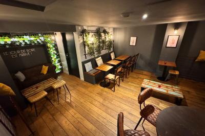 Salle de restaurant chaleureuse avec mobilier en bois, grandes fenêtres et éclairage suspendu.
