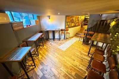 Salle de restaurant chaleureuse avec mobilier en bois, grandes fenêtres et éclairage suspendu.