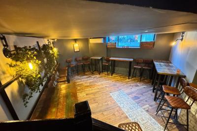 Salle de restaurant chaleureuse avec mobilier en bois, grandes fenêtres et éclairage suspendu.