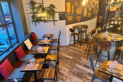 Salle de restaurant chaleureuse avec mobilier en bois, grandes fenêtres et éclairage suspendu.